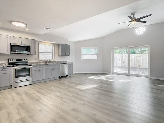 kitchen with stainless steel appliances, vaulted ceiling, ceiling fan, light hardwood / wood-style flooring, and gray cabinets