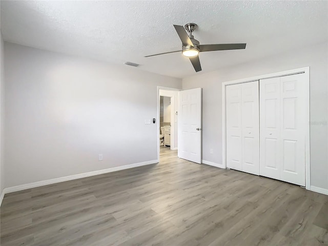 unfurnished bedroom featuring wood-type flooring, a textured ceiling, a closet, and ceiling fan