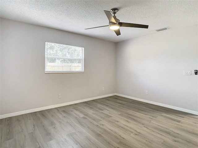 empty room with ceiling fan, wood-type flooring, and a textured ceiling