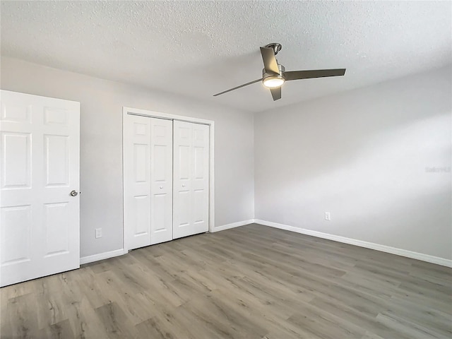 unfurnished bedroom featuring wood-type flooring, a textured ceiling, a closet, and ceiling fan