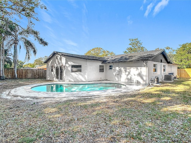 back of house featuring a fenced in pool, a lawn, and central AC unit