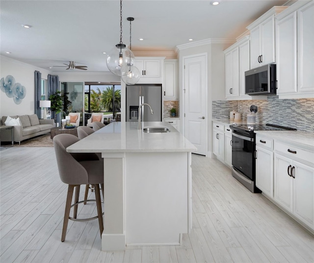 kitchen with stainless steel appliances, white cabinetry, a center island with sink, and sink