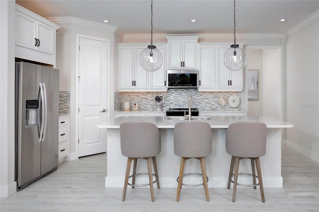 kitchen with white cabinetry, hanging light fixtures, an island with sink, and stainless steel appliances