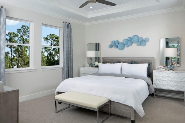 carpeted bedroom with ceiling fan, crown molding, and a tray ceiling