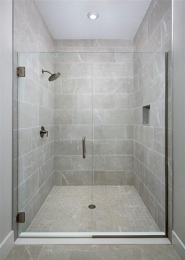 bathroom featuring a textured ceiling and a shower with door