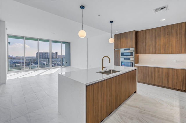 kitchen featuring pendant lighting, a center island with sink, sink, light tile patterned flooring, and stainless steel double oven