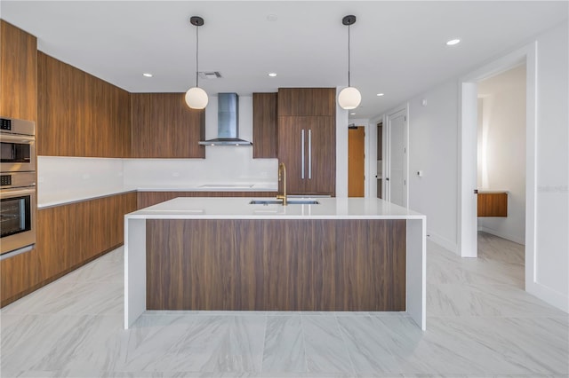 kitchen with pendant lighting, a center island with sink, wall chimney range hood, and sink