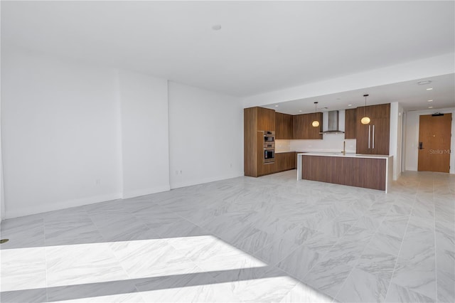 kitchen featuring a center island, double oven, hanging light fixtures, and wall chimney exhaust hood