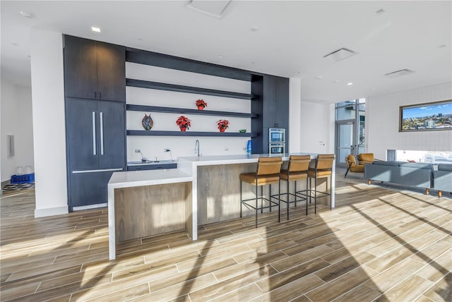 bar featuring double oven, sink, and light hardwood / wood-style floors