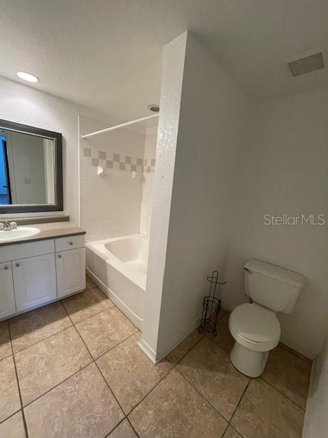 full bathroom featuring tiled shower / bath, tile patterned flooring, vanity, and toilet