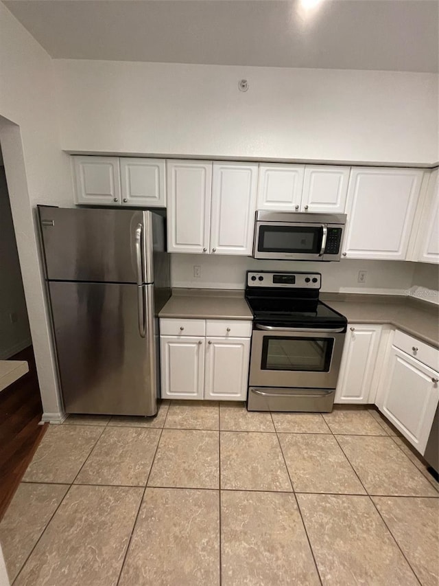 kitchen featuring light tile patterned flooring, white cabinetry, and stainless steel appliances