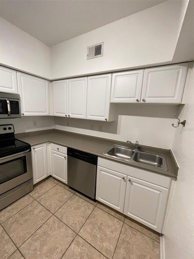 kitchen featuring light tile patterned floors, stainless steel appliances, white cabinetry, and sink