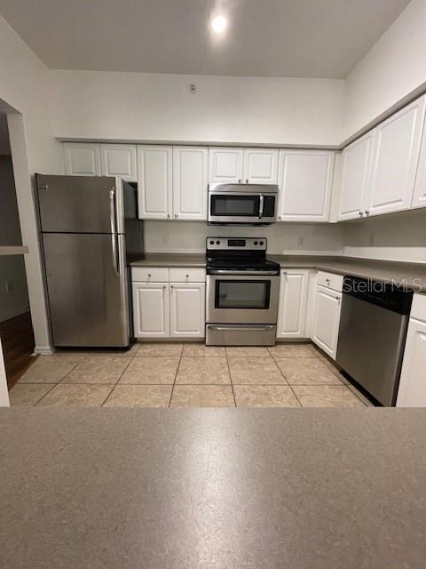 kitchen with white cabinets, light tile patterned floors, and stainless steel appliances