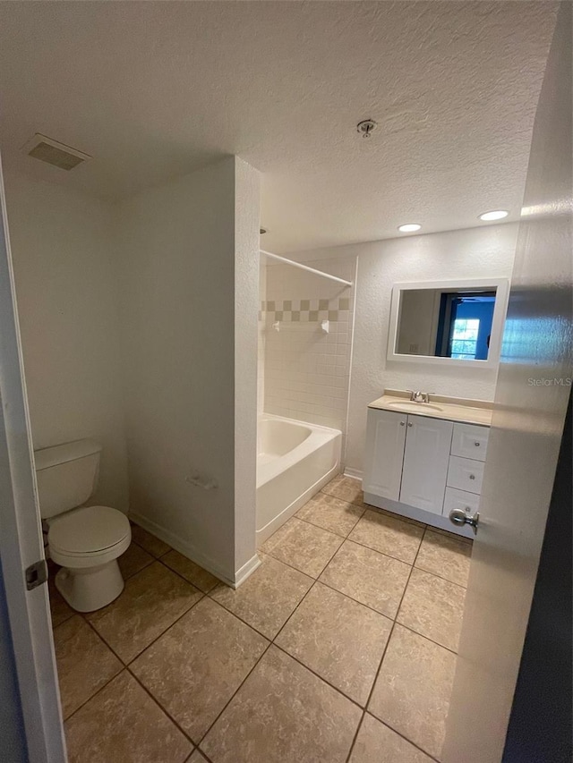 full bathroom with vanity, tile patterned floors, tiled shower / bath, toilet, and a textured ceiling