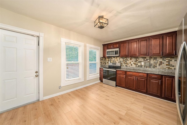 kitchen featuring light stone countertops, appliances with stainless steel finishes, backsplash, and light hardwood / wood-style floors