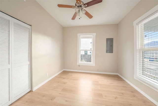 unfurnished bedroom with electric panel, ceiling fan, a closet, and light hardwood / wood-style floors