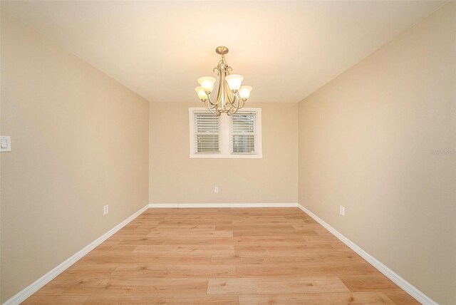 spare room with a chandelier and light hardwood / wood-style floors