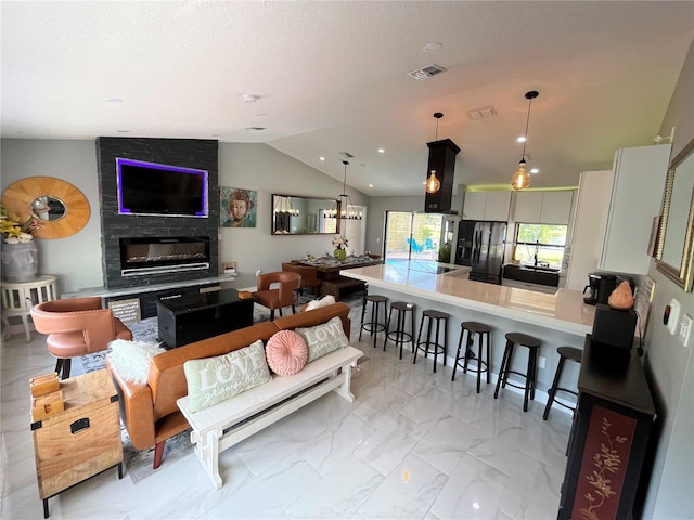 living room featuring a large fireplace, lofted ceiling, and a notable chandelier