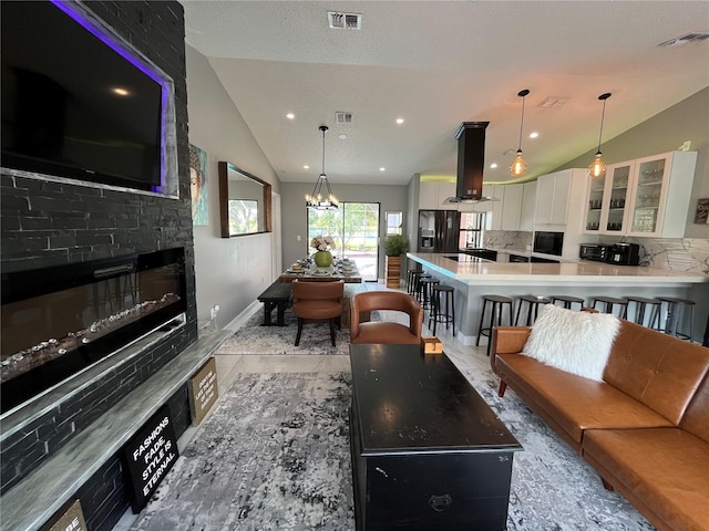 living room featuring a chandelier, a fireplace, and vaulted ceiling