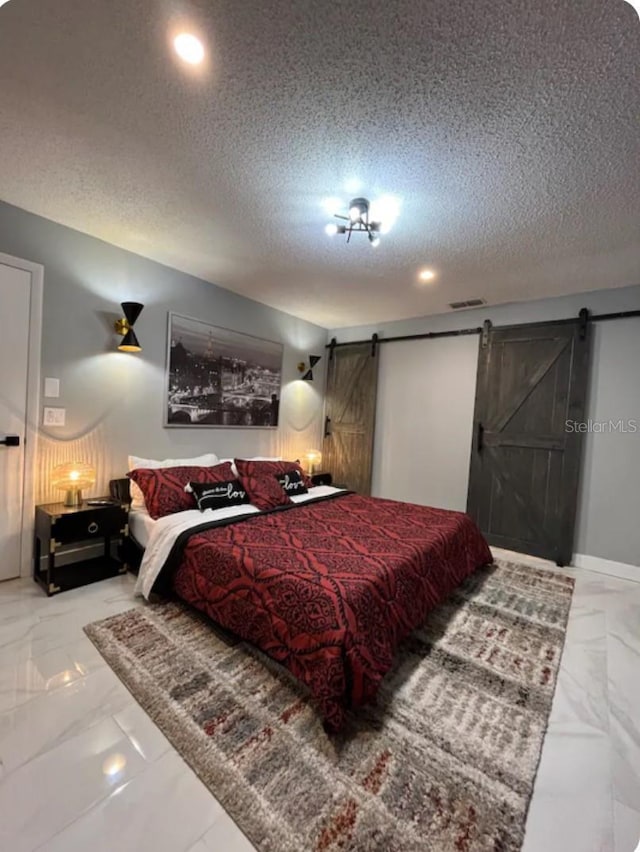 bedroom with a barn door and a textured ceiling