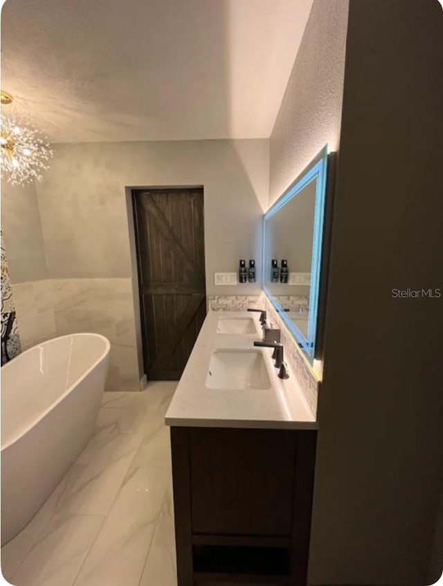 bathroom featuring a washtub, vanity, tile walls, and a notable chandelier