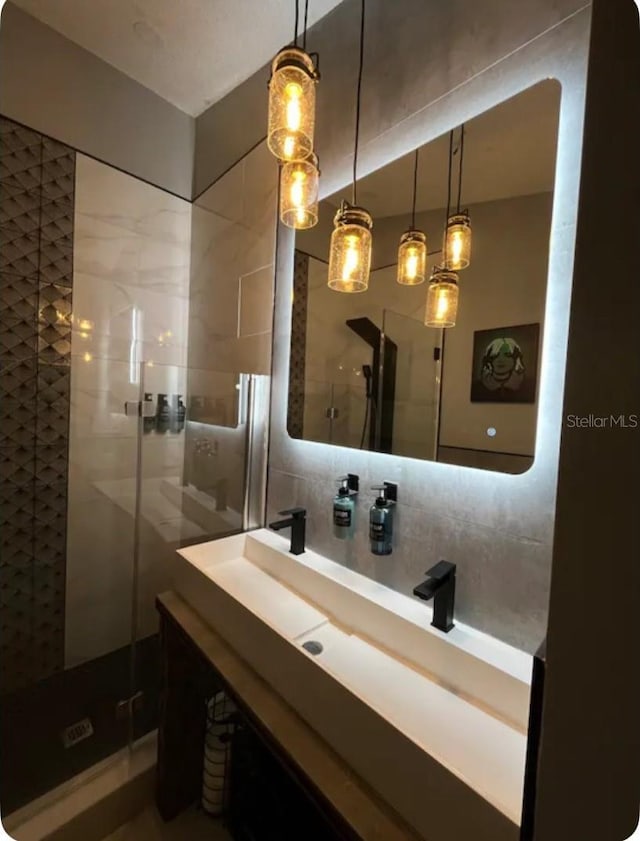 bathroom featuring decorative backsplash, vanity, and a shower with door