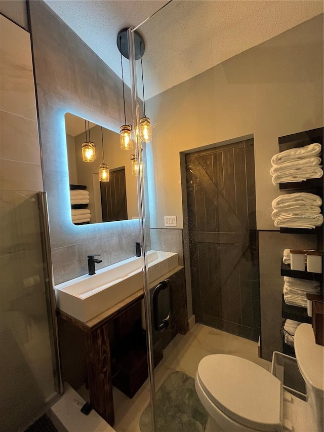 bathroom featuring vanity, a textured ceiling, toilet, and an enclosed shower