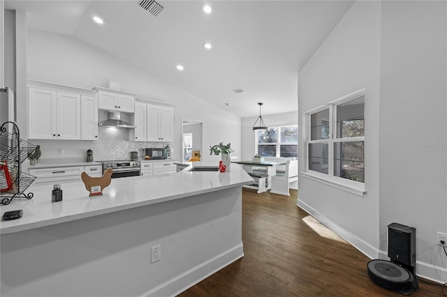 kitchen featuring decorative backsplash, kitchen peninsula, ventilation hood, decorative light fixtures, and white cabinets