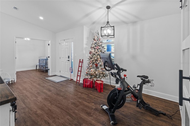 exercise room featuring dark hardwood / wood-style flooring, a chandelier, and vaulted ceiling