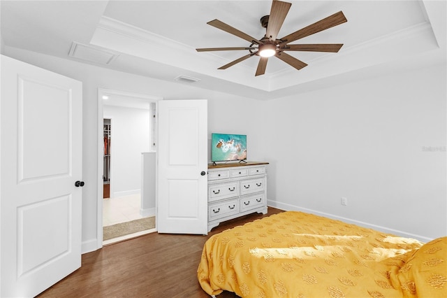 bedroom with a tray ceiling, ceiling fan, ornamental molding, and dark hardwood / wood-style floors