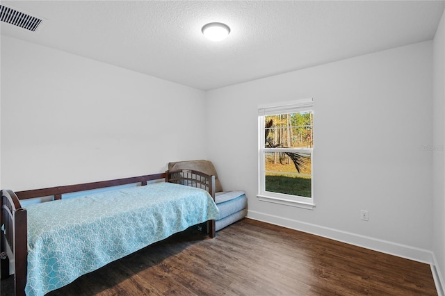 bedroom featuring a textured ceiling and dark hardwood / wood-style floors