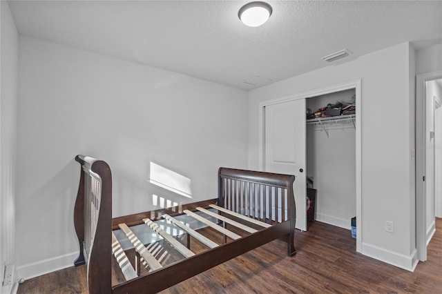 bedroom featuring a textured ceiling, dark hardwood / wood-style floors, and a closet