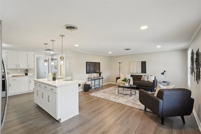 kitchen with white cabinetry, a kitchen island, hanging light fixtures, and light hardwood / wood-style floors