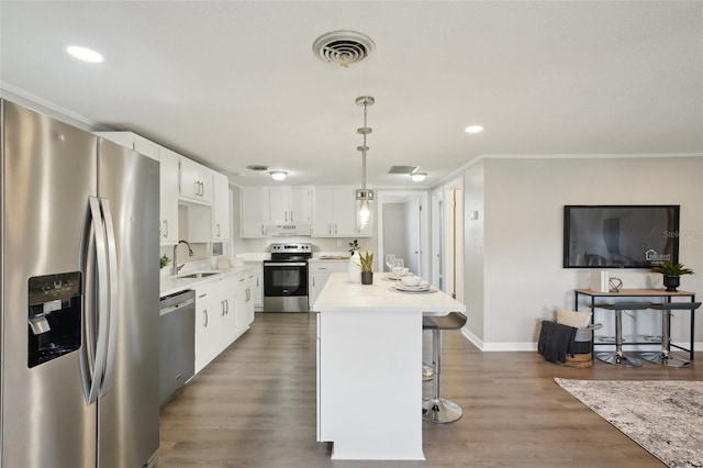 kitchen featuring white cabinetry, sink, decorative light fixtures, a kitchen island, and appliances with stainless steel finishes