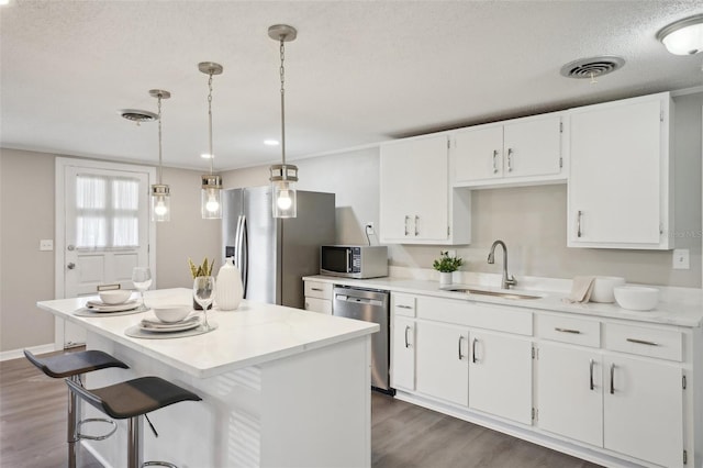 kitchen with white cabinetry, sink, a center island, hanging light fixtures, and stainless steel appliances