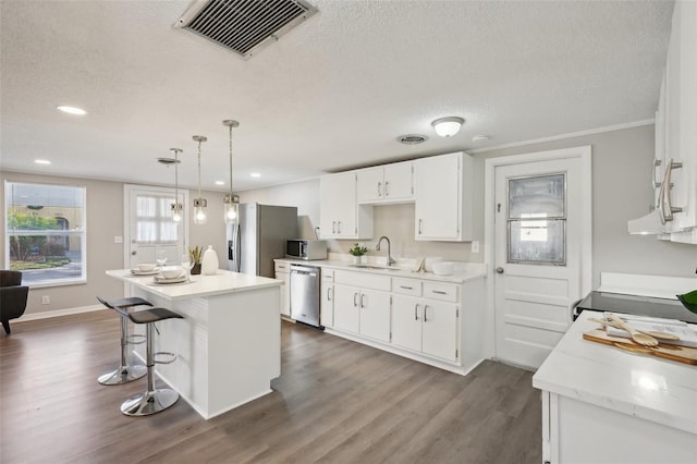 kitchen featuring white cabinetry, sink, dark wood-type flooring, stainless steel appliances, and decorative light fixtures