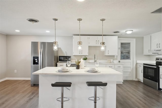 kitchen with appliances with stainless steel finishes, white cabinetry, and a kitchen island