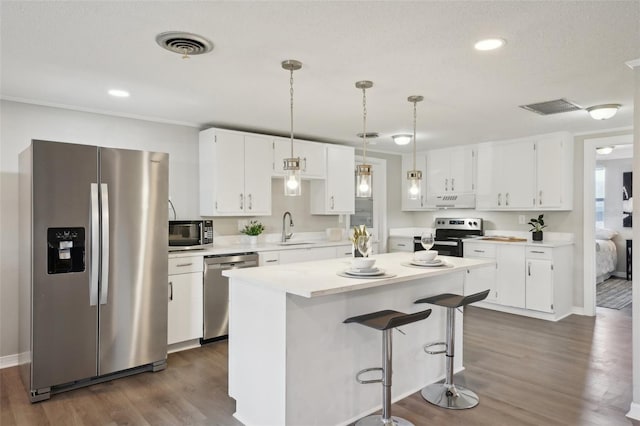 kitchen featuring appliances with stainless steel finishes, dark hardwood / wood-style flooring, sink, pendant lighting, and white cabinetry