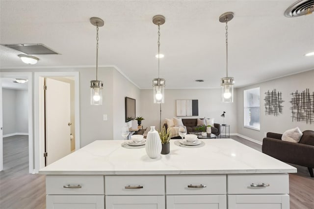 kitchen with a center island, light hardwood / wood-style floors, white cabinetry, and hanging light fixtures