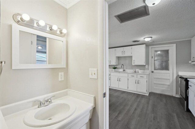 bathroom featuring vanity, wood-type flooring, a textured ceiling, and ornamental molding