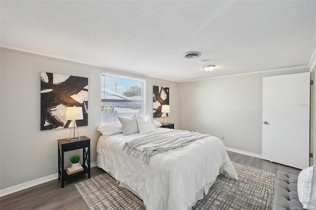 bedroom with dark wood-type flooring, a textured ceiling, and ornamental molding