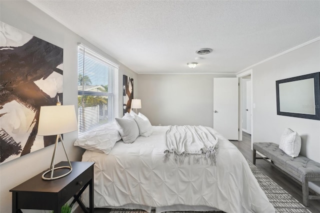 bedroom featuring crown molding, wood-type flooring, and a textured ceiling