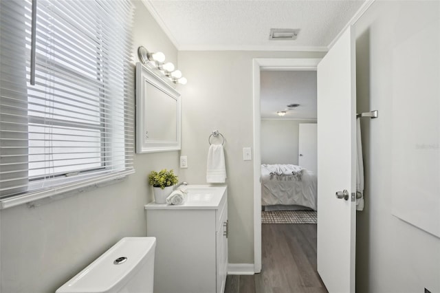 bathroom featuring crown molding, a textured ceiling, toilet, vanity, and hardwood / wood-style flooring