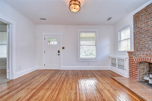 foyer entrance with a fireplace, light hardwood / wood-style floors, plenty of natural light, and ornamental molding