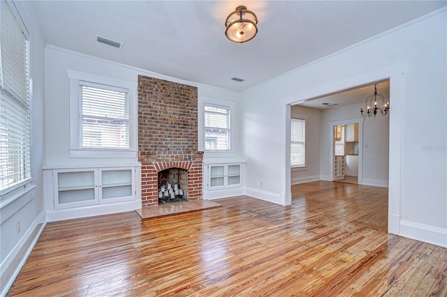 unfurnished living room featuring light hardwood / wood-style floors, a brick fireplace, and a healthy amount of sunlight