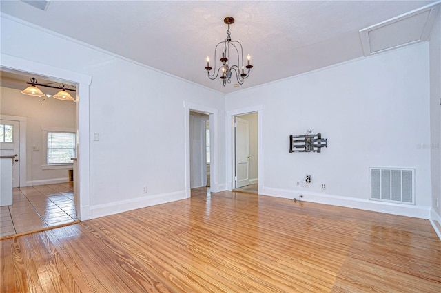 spare room with crown molding, light hardwood / wood-style floors, and a notable chandelier