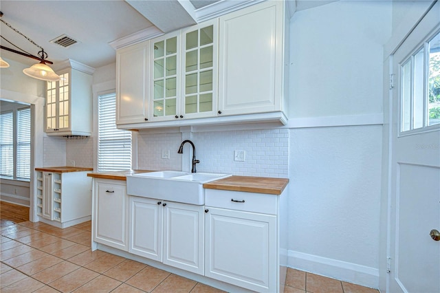 kitchen with white cabinets, butcher block counters, and hanging light fixtures