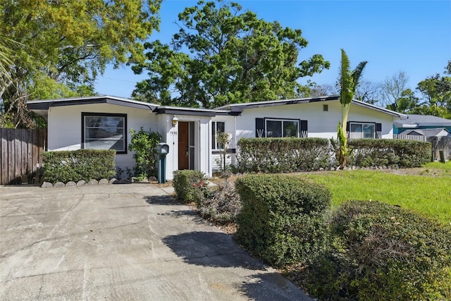 single story home featuring concrete driveway, a front lawn, and fence