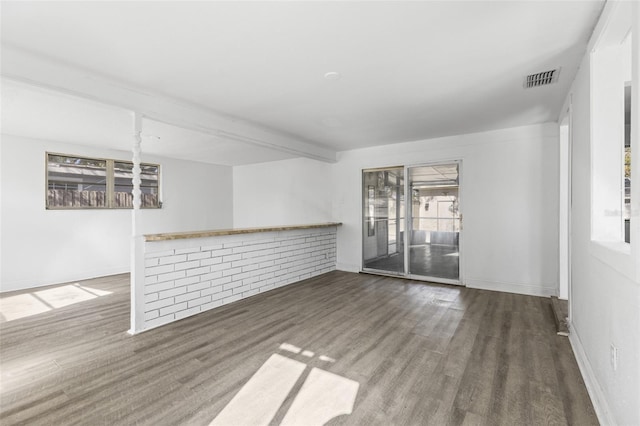 spare room with beam ceiling, wood finished floors, visible vents, and baseboards