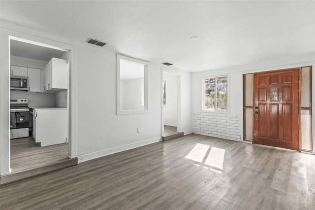 unfurnished living room featuring visible vents, baseboards, and wood finished floors